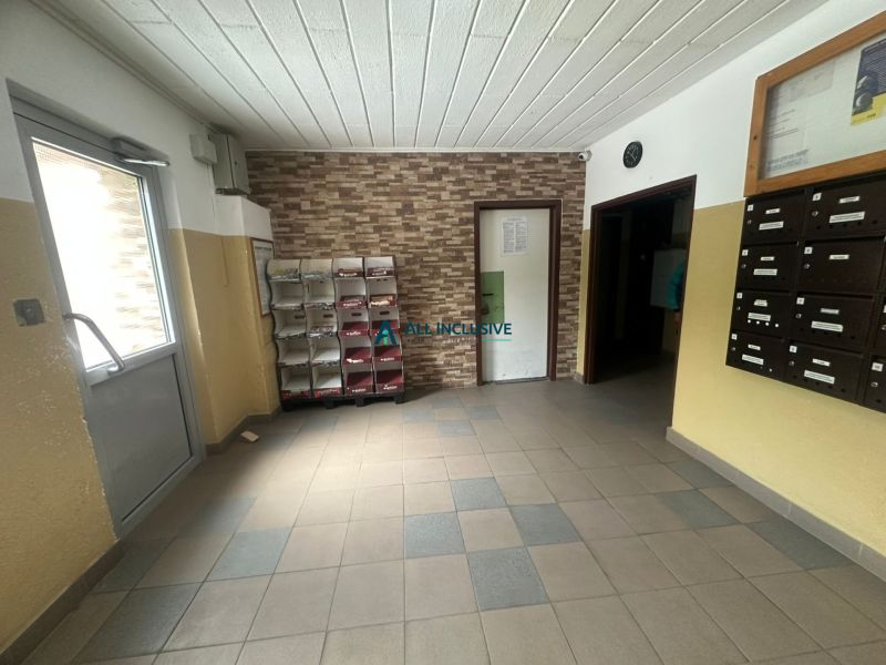 A lakóház bejárati folyosója csempével és postaládákkal, egy kétszobás lakásban.