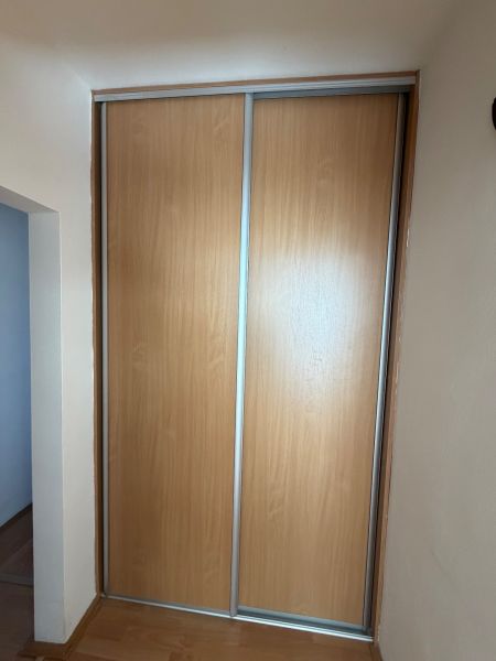 Tolóajtós szekrény és fa dekorációjú padló a háromszobás lakásban.