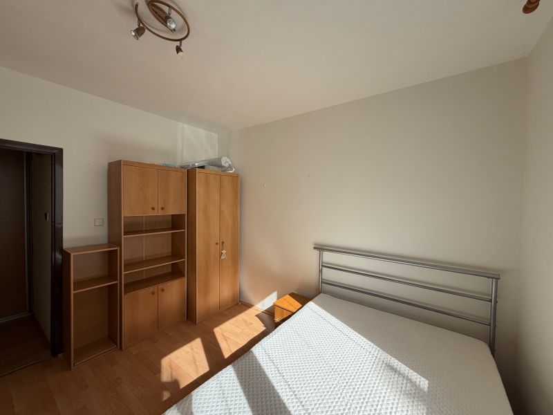 Hálószoba egy háromszobás lakásban fehér falakkal és fa dekoros padlóval.