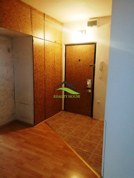 Bejárati folyosó fa dekor padlóval egy háromszobás lakásban, gardróbszekrényekkel.