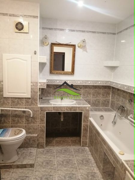 Háromszobás lakás fürdőszobája káddal, tükörrel és WC-vel, csempével burkolva.
