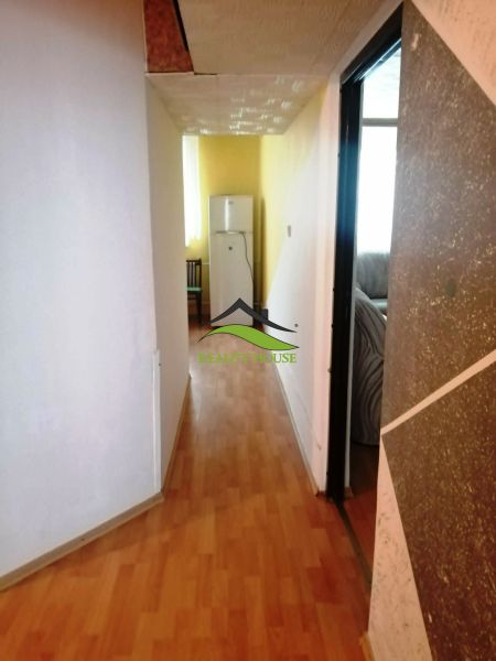 Folyosó egy háromszobás lakásban fa dekoros padlóval, amely a hűtőszekrényhez vezet.