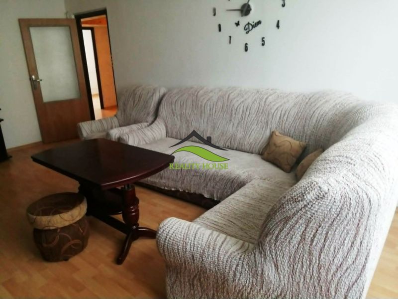 Nappali egy háromszobás lakásban sarokkanapéval és fa dekorációjú padlóval.