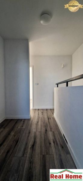 Folyosó egy családi házban, fa dekoros padlóval és fehér falakkal.