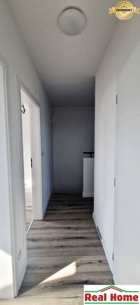 Egy családi ház folyosója fehér falakkal és fa dekorációjú padlóval.