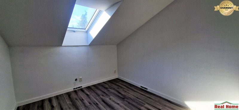 Tetőtéri szoba nagy tetőablakkal és fa dekorációjú padlóval egy családi házban.