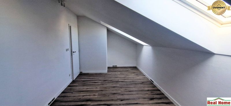 Tetőtér egy családi házban fa mintázatú padlóval és tetőablakkal.