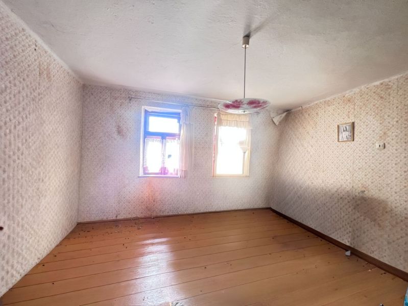 Üres szoba egy családi házban, fa dekoros padlóval és virágos csillárral.