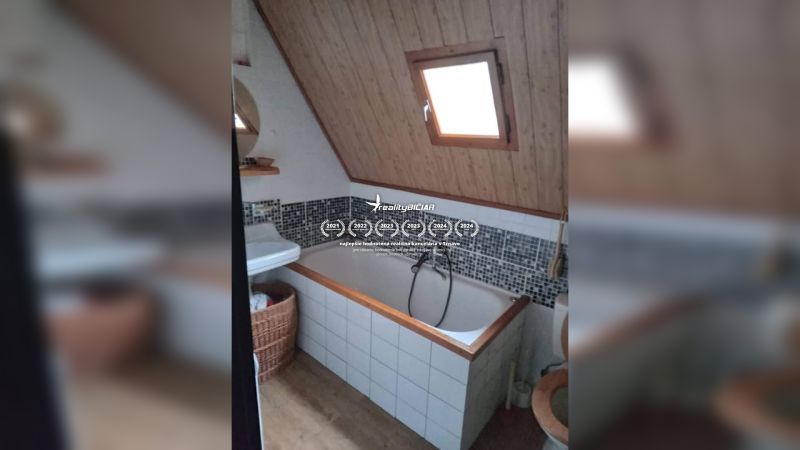 Fürdőszoba káddal és ferde mennyezettel, fa dekoráció, mozaik csempe, ablak.