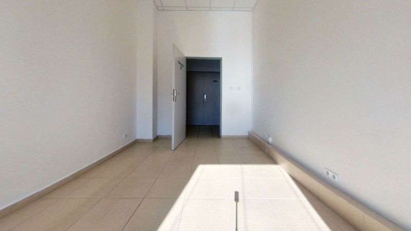 Iroda belső tér fehér falakkal és világos kerámia padlóburkolattal.