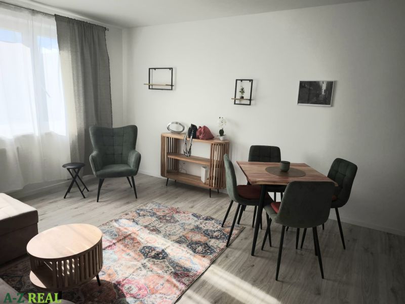 Nappali egy kétszobás lakásban zöld fotellel és fa padló dekorációval.