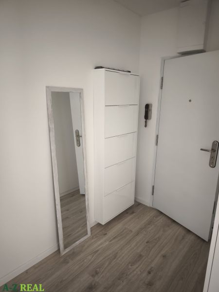 Előszoba fehér bútorokkal és fa dekorációjú padlóval egy kétszobás lakásban.