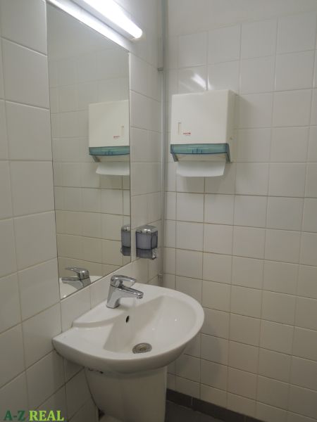 Mosdó a irodákban szappanadagolóval és tükörrel a falon.