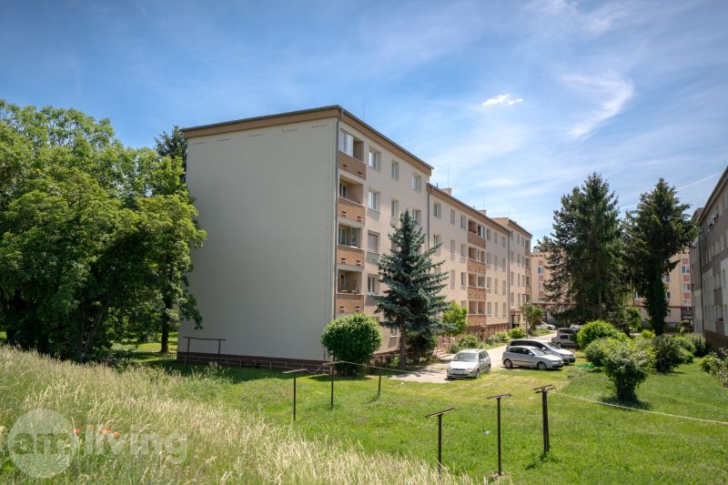 A Švermova utcai lakóházak Trencsénben a környező zöldterülettel és parkoló autókkal.