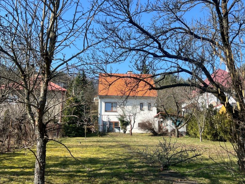 Családi ház Podhájban, Kráľovában, fákkal és gyepes területtel körülvéve, narancssárga tetővel.