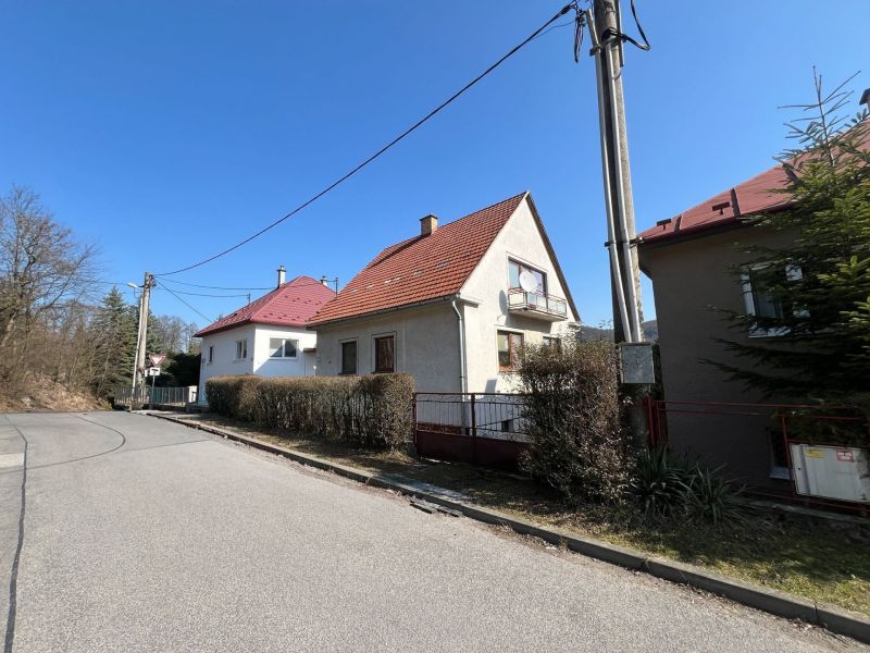 Családi ház Podhájban, Kráľová, Besztercebánya. Keskeny járda, bokrok, villanyoszlop.