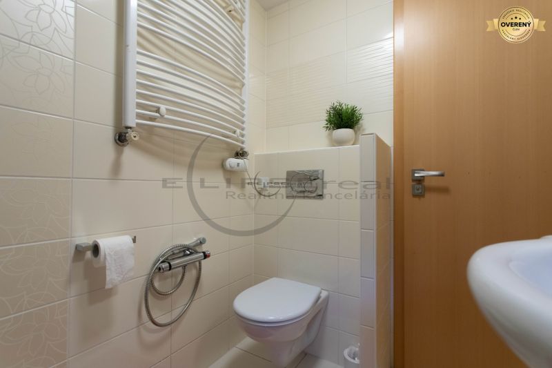 Fürdőszoba kerámia burkolattal, WC-vel és fűtött törölközőszárítóval egy családi házban.