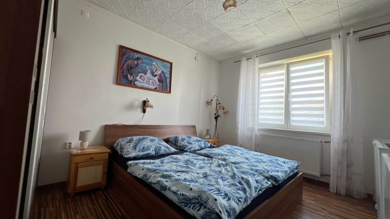 Hálószoba egy háromszobás lakásban, ággyal és képpel a falon.