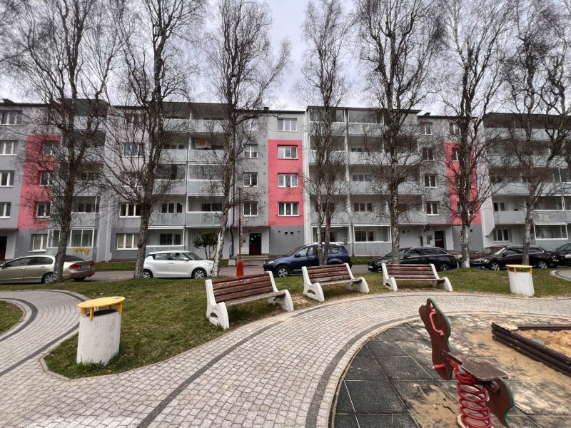 Egy lakóház Rózsahegyen, fákkal és parkolóhelyekkel a kétszobás lakások előtt.