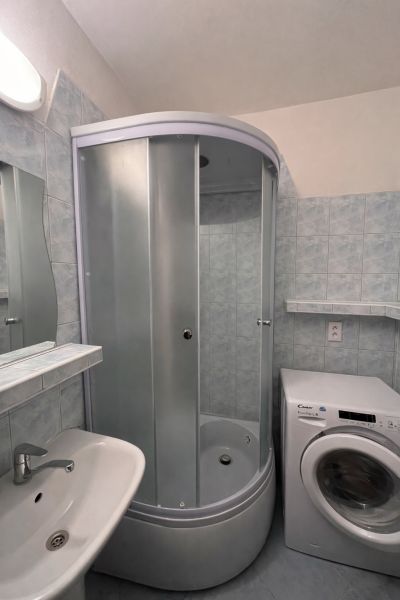 Fürdőszoba zuhanyzóval és mosógéppel egy kétszobás lakásban.