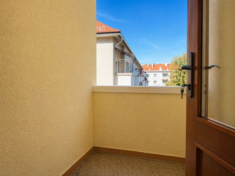 Erkély egy 4 szobás lakásban, kilátással a tetőkre és fákra.