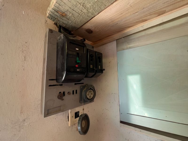 Régi elektromos elosztószekrény a garázsban, régi biztosítékokkal és aljzatokkal.