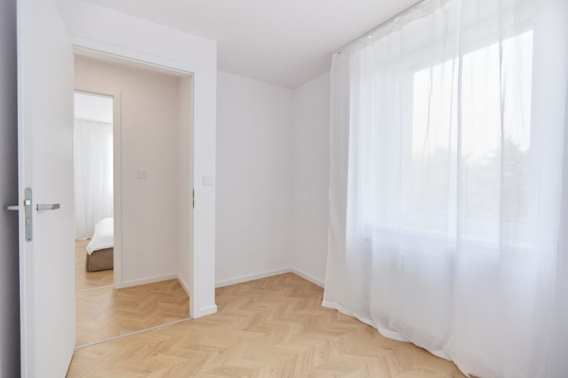 Szoba fehér függönyökkel és fa dekorációjú padlóval egy 4 szobás lakásban.
