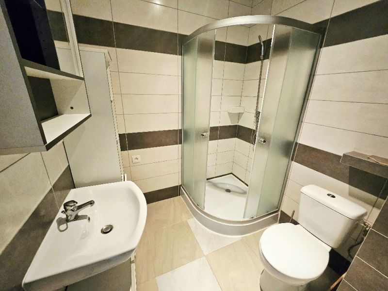 Fürdőszoba egy egyszobás lakásban mosdóval, zuhanyzóval és WC-vel.