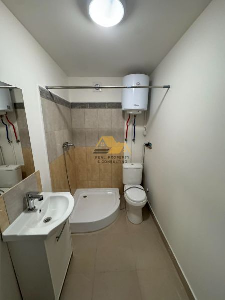Fürdőszoba egy kétszobás lakásban káddal, mosdóval és WC-vel, világos csempe a falakon.