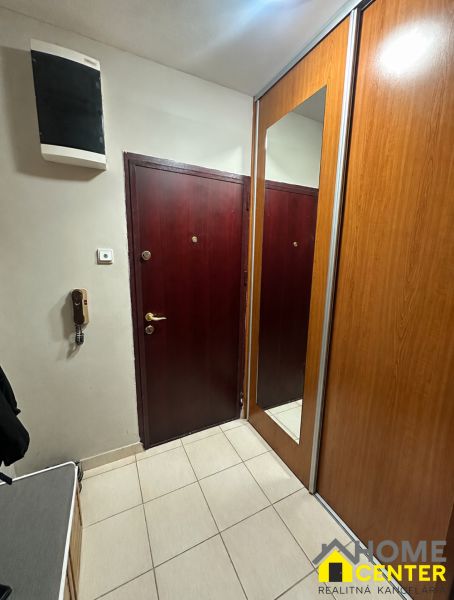 Előszoba egy háromszobás lakásban tükrös gardróbszekrénnyel és világos csempével.
