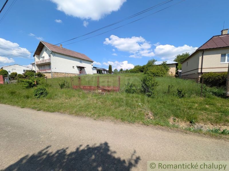 Zölddel körülvett ház Karnán, kerítéssel szegélyezve, ideális lakóingatlanok számára.