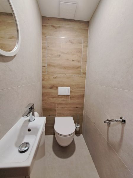 Fürdőszoba egy kétszobás lakásban, fa dekoros padlóval és fali WC-vel.