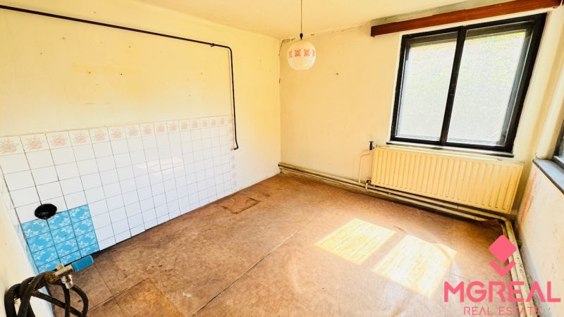 Üres szoba ablakkal, radiátorral és fa dekorációjú padlóval egy családi házban.