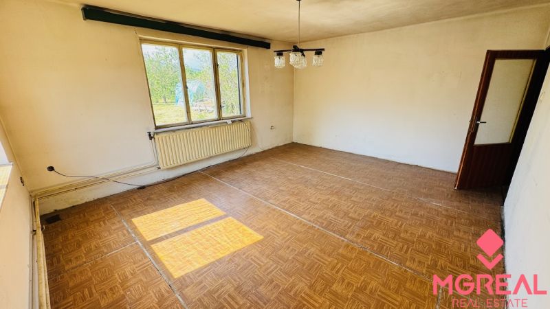 Szoba fa dekorációjú padlóval, nagy ablakkal és radiátorral egy családi házban.