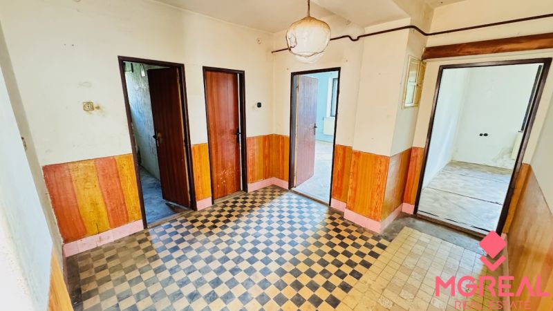 Folyosó egy családi házban, csempével és fa dekorációval a falakon.