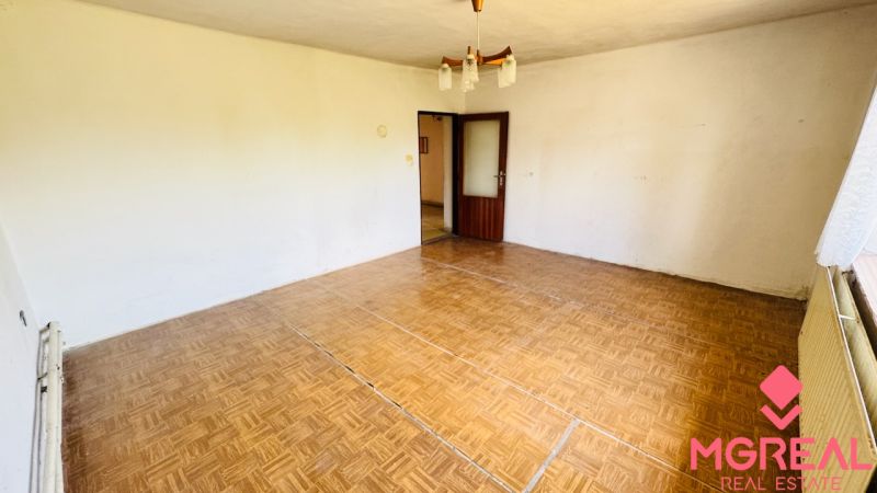 Szoba egy családi házban fa dekorációjú padlóval és csillárral.