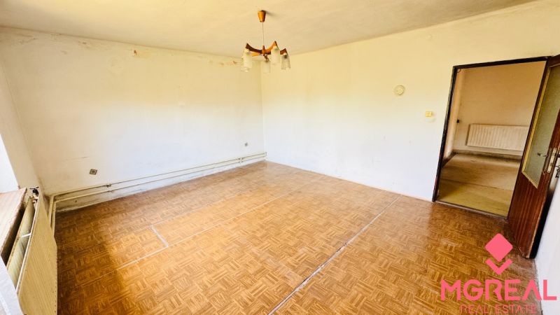 Nappali egy családi házban, fa mintázatú padlóval és egyszerű világítással.