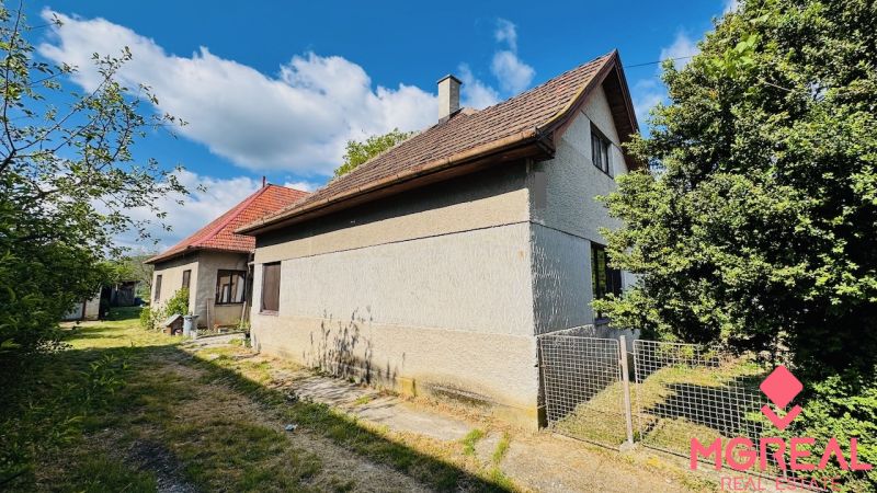Családi ház Pažiťban, zölddel körülvéve, piros tetővel és fa ablakokkal.