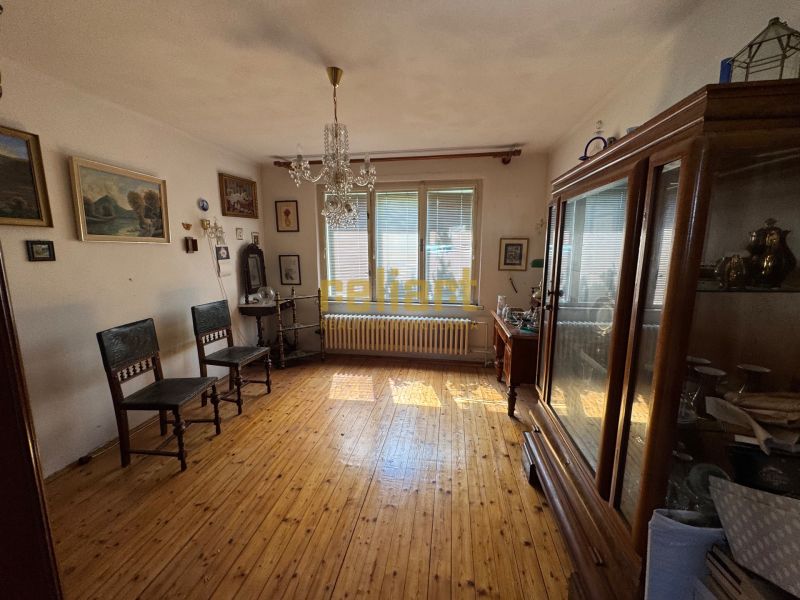 Egy szoba családi házban fa dekorációval, vintage bútorokkal és sok festménnyel a falakon.