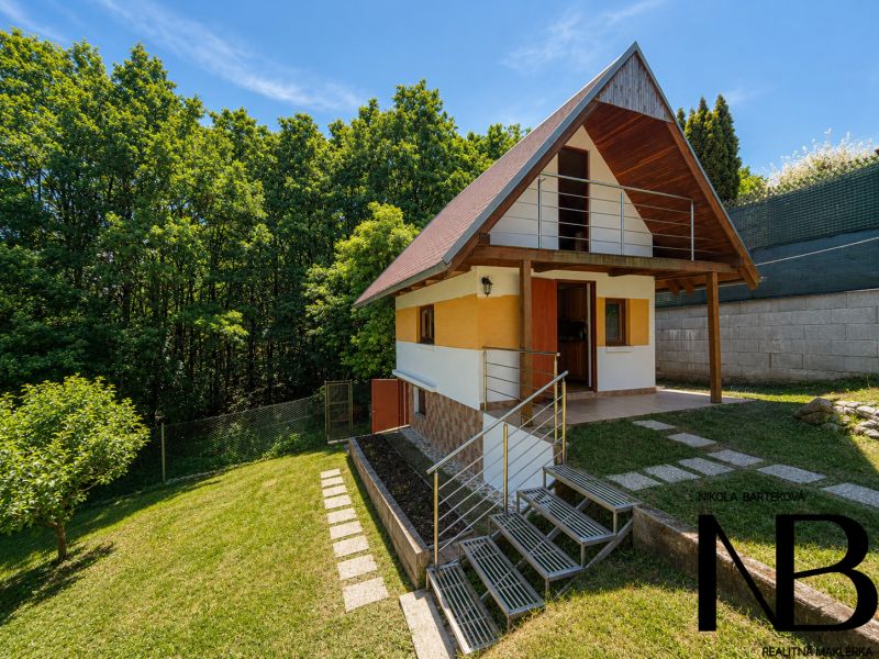 Faház fa dekorációval Považská Bystricában, Klučina területén, zölddel és fákkal körülvéve.