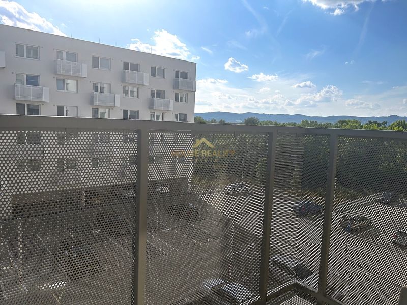 Erkély egy egyszobás lakásban, kilátással a parkolóra és a környező hegyekre.