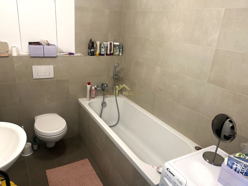 Fürdőszoba káddal, WC-vel és mosógéppel egy egyszobás lakásban.