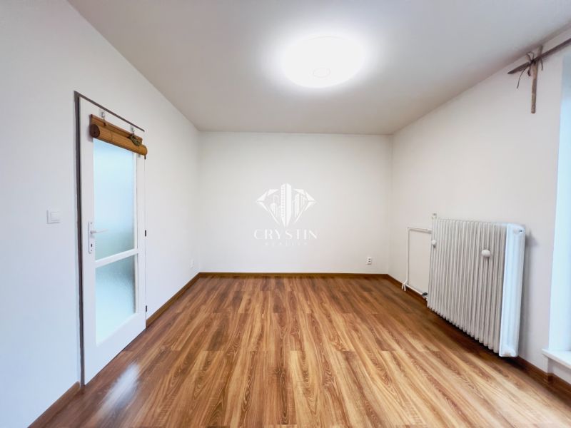 Szoba egy kétszobás lakásban fa dekor padlóval és radiátorral.