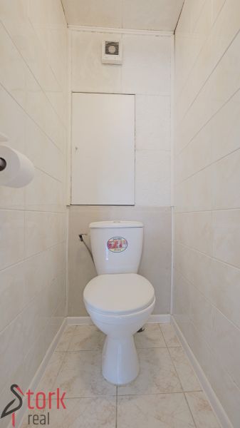A háromszobás lakás fürdőszobája fehér csempékkel és WC-vel.