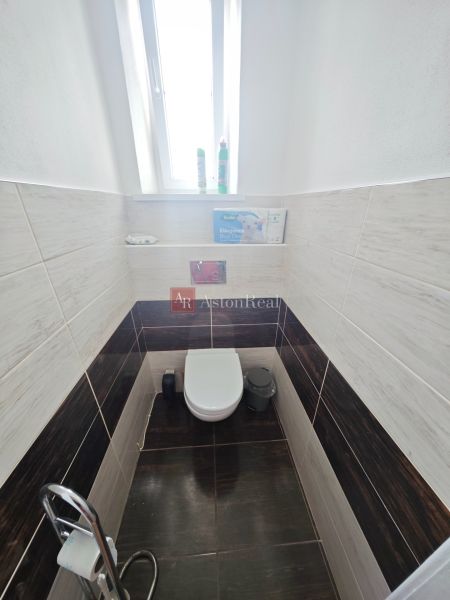 Fürdőszoba WC-vel egy kétszobás lakásban, fa dekorációs burkolatokkal a falakon.