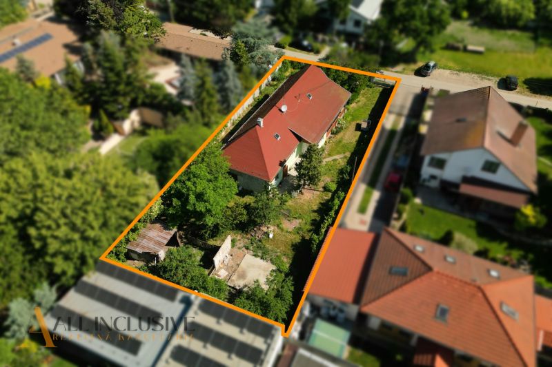 Családi ház Hviezdoslavovban piros tetővel, zölddel és más épületekkel körülvéve.