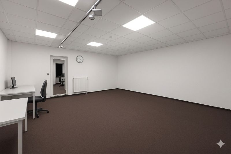 Priestranné Kancelárie s bielymi stenami, hnedým kobercom a minimalistickým zariadením.