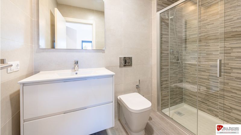 Fürdőszoba a nyaraló apartmanban nagy zuhanyzóval és elegáns mosdóval.