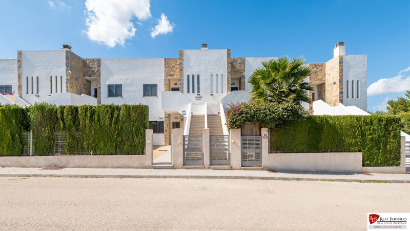 Nyaraló apartman Cala Muradában, Mallorcán, modern homlokzattal és zöld sövénnyel.