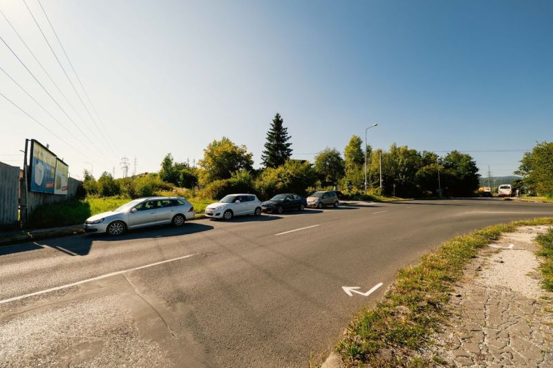 Út parkoló autókkal és hirdetőtáblával a Partizánska úton, Besztercebánya, Lakóterületek.